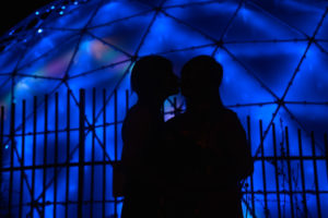 Photographers of Las Vegas - Wedding Photography - wedding couple shadows couple kiss with neon dome behind at container park