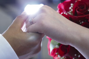 Photographers of Las Vegas - Wedding Photography - wedding rings on hands with flowers light behind