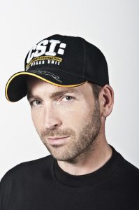 Photographers Of Las Vegas - Headshot Photography - Man with CSI Las Vegas Unit hat. Man with black shirt and black hat. Man with hat and blue eyes. Man wearing black with white backdrop