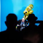 Photographers Of Las Vegas - Corporate Photography - presentation theater audience yellow emoji balloons crowd silhouette man riding moped