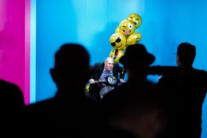 Photographers Of Las Vegas - Corporate Photography - presentation theater audience yellow emoji balloons crowd silhouette man riding moped