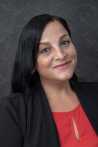 Photographers Of Las Vegas - Headshot Photography - Woman with grey texture background. Woman wearing black blazer and red blouse. Women professional attire. Black hair and gray backdrop