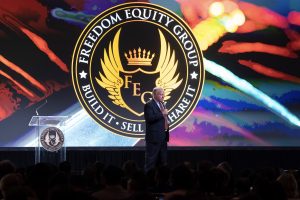 Photographers Of Las Vegas - Event Photography - Man hosting blue suit red tie freedom equity group colorful backdrop