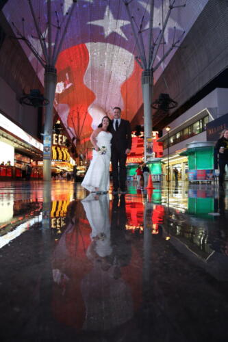 Photographers of Las Vegas - Wedding Photography - Couple reflected in rain water on Fremont Street